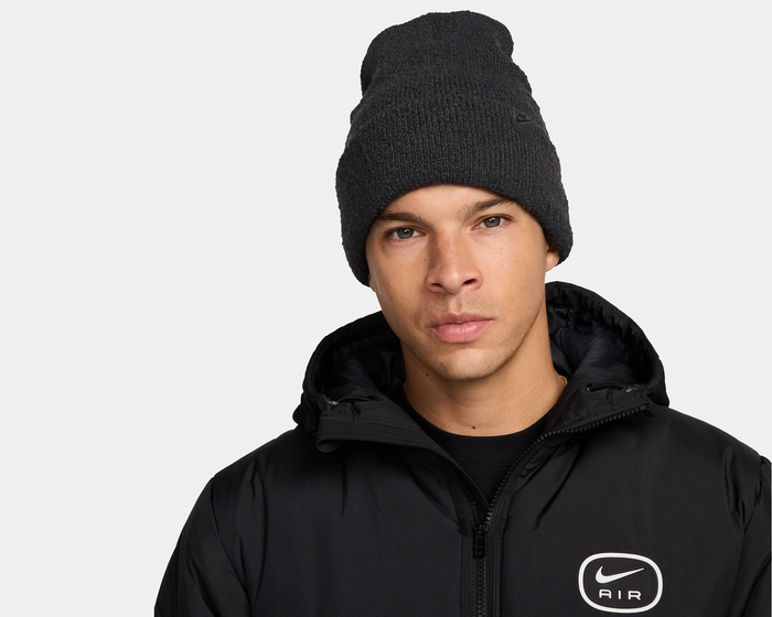 Nike Peak knit beanie in dark gray featuring textured material and subtle logo detailing, front view in lifestyle context.