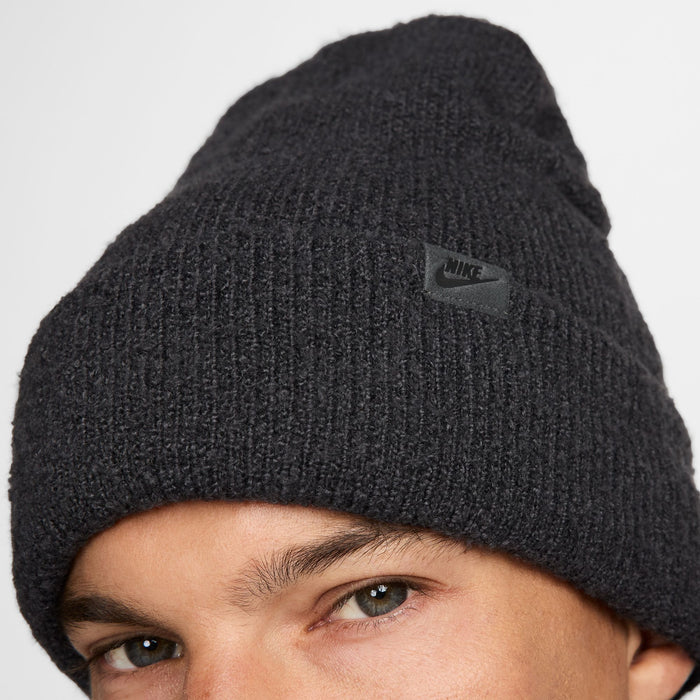 Nike Peak beanie in black with ribbed knit texture and subtle logo patch on the fold-over cuff, front view.