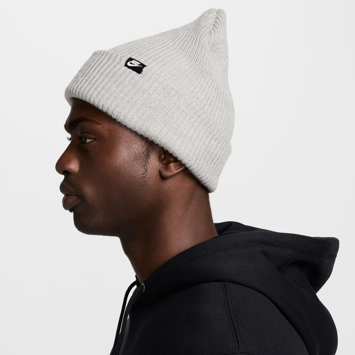 Nike Peak knit beanie in light gray featuring ribbed texture and black logo patch on the side, side view.