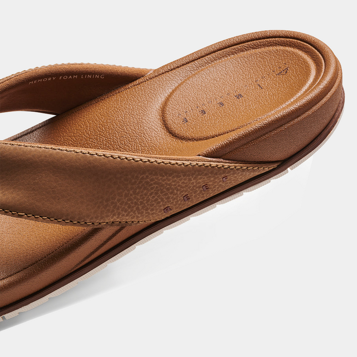 Reef Phantom Bronzer flip-flops in brown with synthetic strap and memory foam lining, close-up side view showing footbed details.