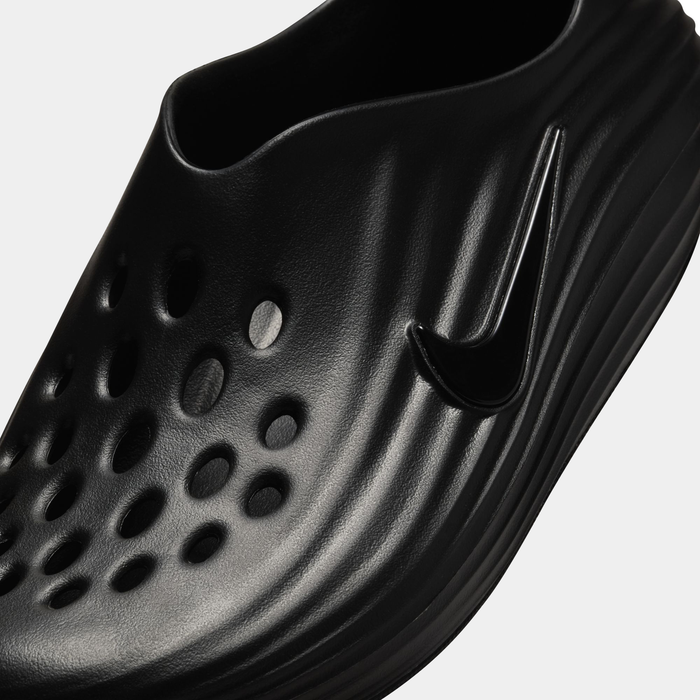 Nike ReactX Rejuven8 slip-on shoes in black, textured design with perforated details and embossed Nike Swoosh logo, close-up toe box view.