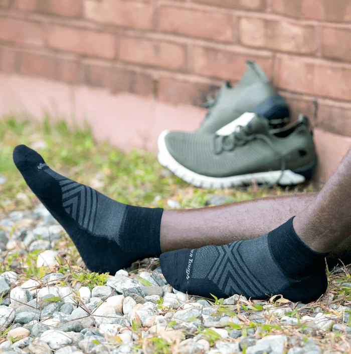 Darn Tough Run Quarter Ultra-Lightweight Running Socks in black with subtle stripe pattern and ultra-light fabric, worn outdoors.