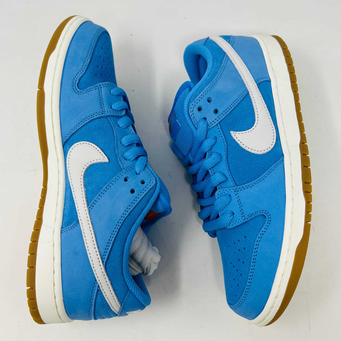 The Nike SB Dunk Low Pro University Blue Gum sneaker, featuring a white swoosh, laces, midsole, and gum-colored outsole, is placed on a brown shoebox with an orange swoosh against a plain white background.