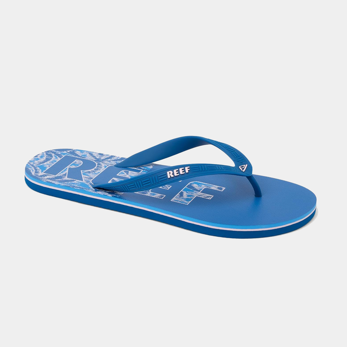 Reef Seaside Prints flip flops in blue with wave pattern and logo on footbed, side view.