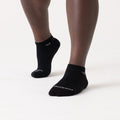 A pair of black no-show socks on a person's feet, showing the side profile with the brand name visible on the foot area.