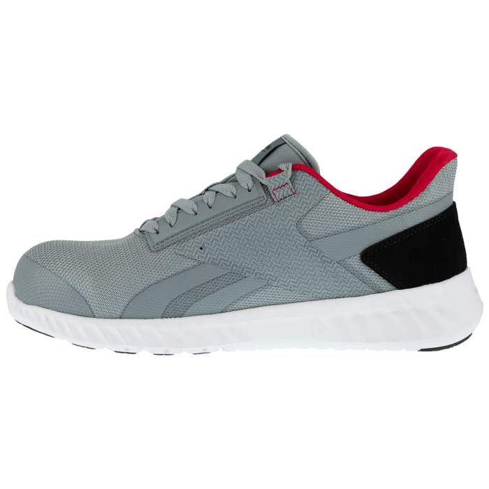 Reebok Work Sublite Legend Work shoes in gray with mesh upper, black heel accent, red inner lining, and white sole, side view.