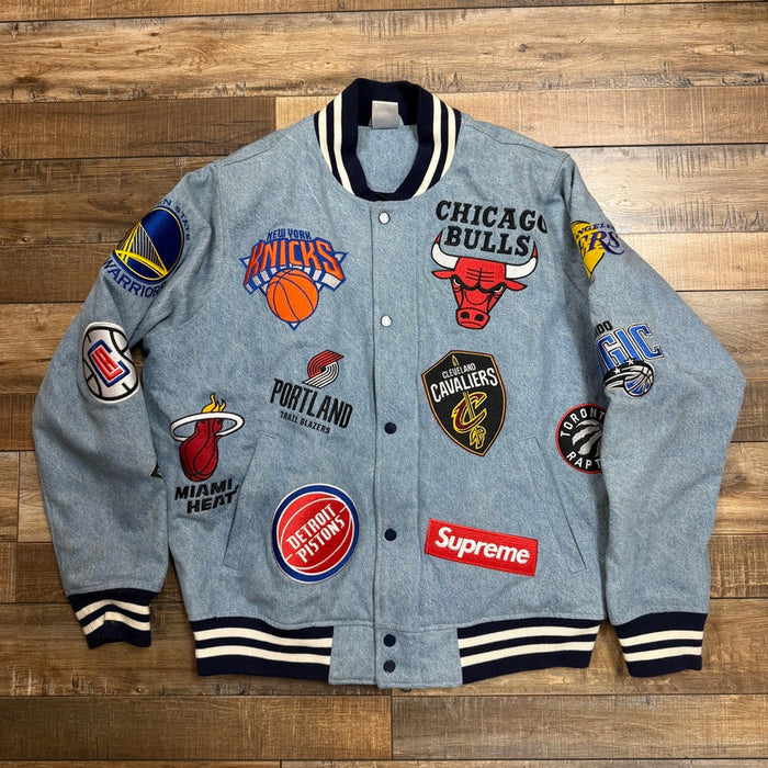 The preowned Supreme Nike/NBA Teams Warm-Up Jacket Denim features a gray design with a black collar and cuffs, adorned with embroidered NBA team logos, including the Bulls, Knicks, Heat, and more. It also sports a red Supreme patch on the front.
