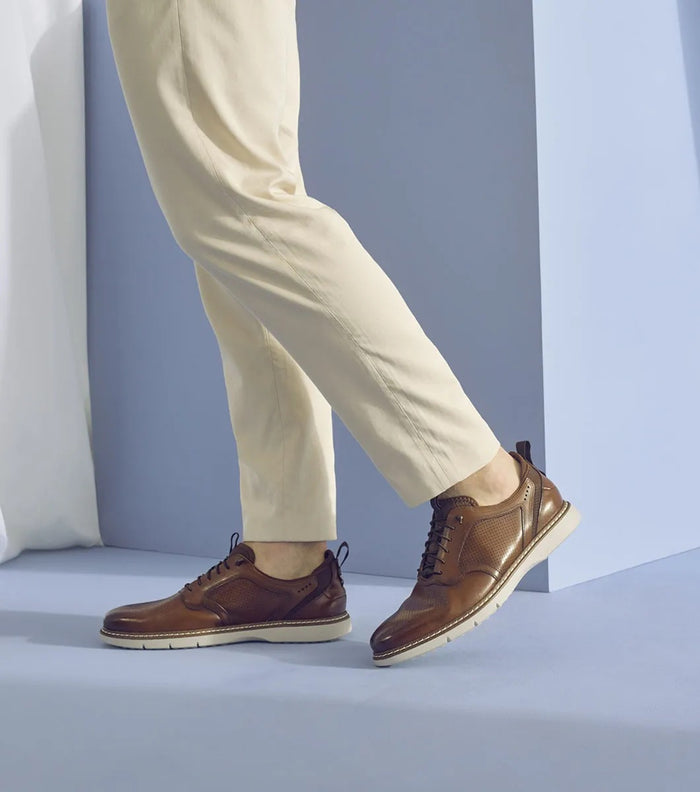 Stacy Adams Sync Plain Toe shoes in brown leather with perforated detailing and white rubber sole, worn by a person walking.