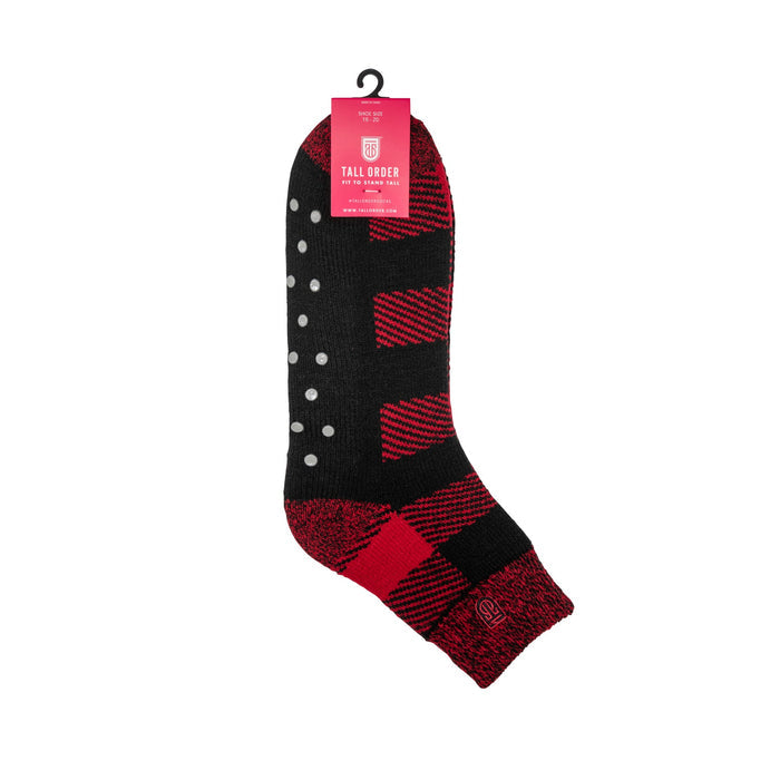 Tall Order The Cabin Slipper Socks in black and red with non-slip grip dots and plaid pattern, side view showing design and packaging.