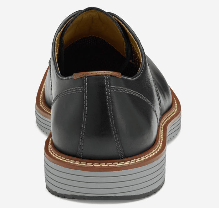 Johnston & Murphy Upton Plain Toe dress shoes in black leather with contrast stitching and textured gray and brown sole, back view.