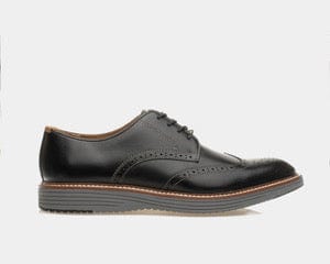 Johnston & Murphy Upton Wingtip dress shoes in black leather with brogue detailing and contrast stitching, side view.