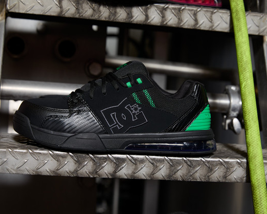DC WorkCrew Versatile Work Comp Toe shoes in black with green accents, composite toe, durable leather upper, side view on metal stairs.