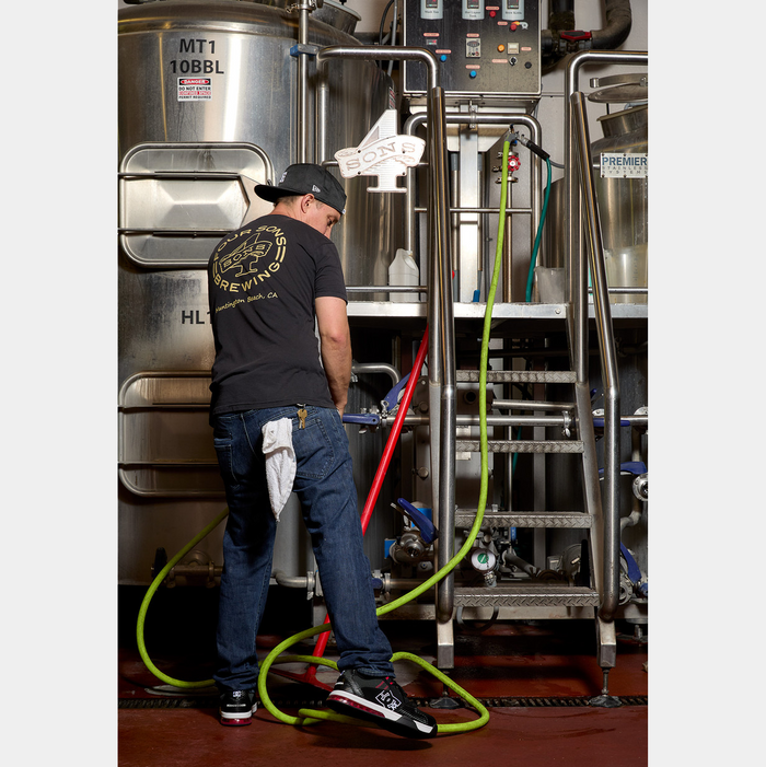 DC WorkCrew Versatile Work Comp Toe shoes in black, white, and red with a durable design, worn by a worker in an industrial brewery setting.