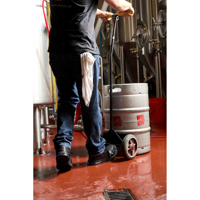 DC WorkCrew Versatile Work Hi Top Comp Toe work shoes in black with high-top design and composite toe, worn by worker in brewery setting.