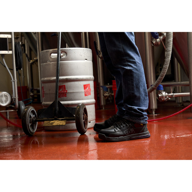DC WorkCrew Versatile Work Hi Top Comp Toe work shoes in black with high-top design and protective composite toe, worn by worker in industrial setting.