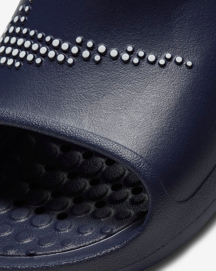 Nike Victori One Shower slides in navy blue with textured sole and perforations for drainage, close-up view of strap design.
