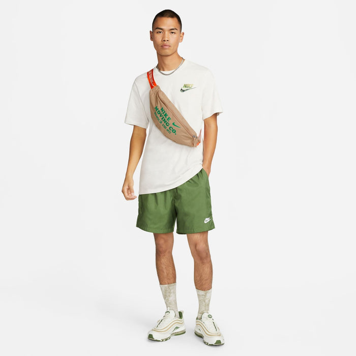 Nike Waist Pack in beige with green text and orange adjustable strap, worn across the chest.
