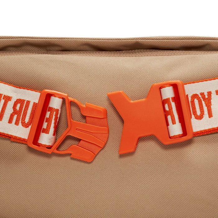 Nike Waist Pack in beige with orange buckle and white strap featuring orange text detail, close-up view of strap and buckle.